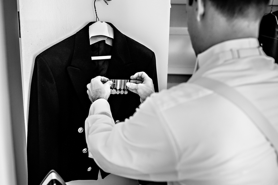A groom pinning his Navy metals to his jacket.